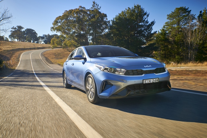 Blue Kia Cerato Sport Plus compact car on a winding road
