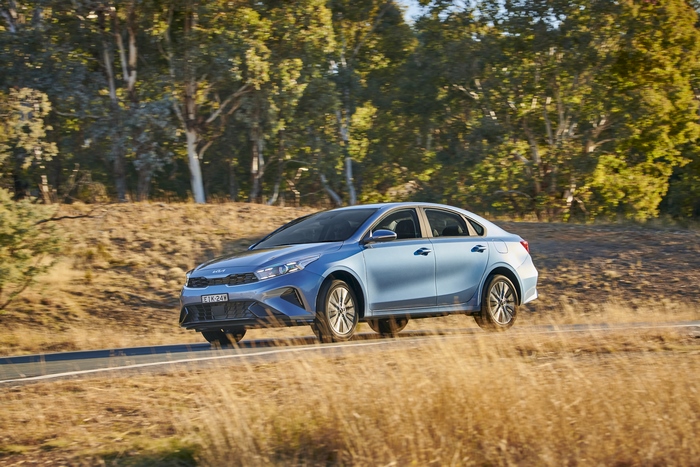 Blue Kia Cerato Sport Plus compact car driving on a road