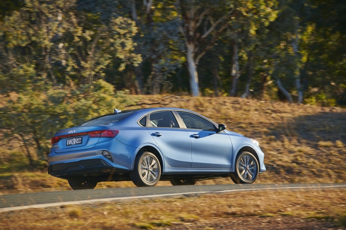 Blue Kia Cerato Sport Plus driving on a scenic road