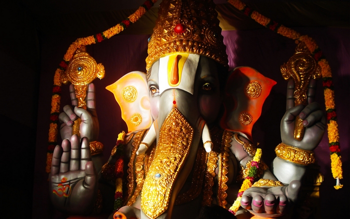 Ganesh statue adorned with gold in dramatic lighting
