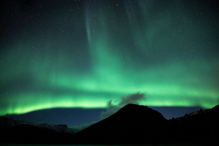 Aurora Borealis over mountains and starry night