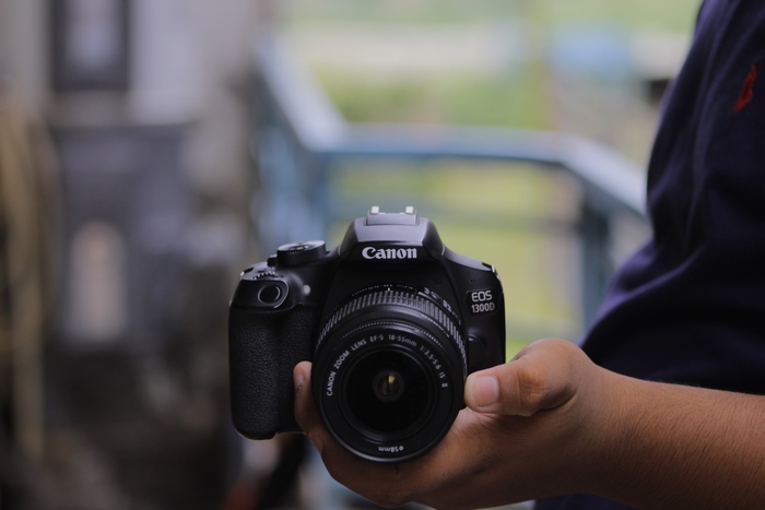 Hand holding Canon EOS 1300D DSLR camera