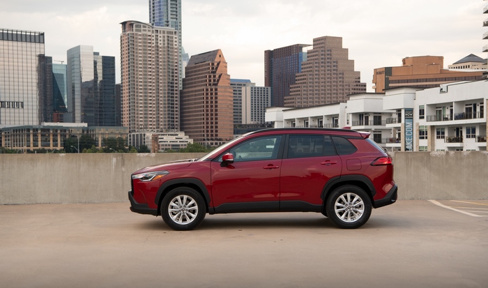 Red Toyota Corolla Cross SUV with city skyline