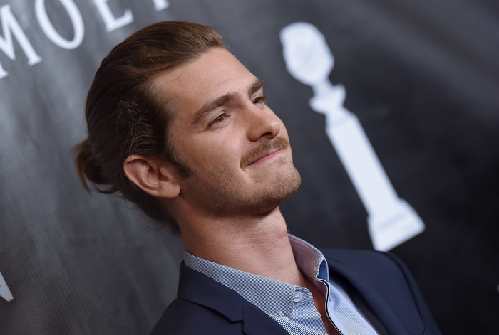 Andrew Garfield smiling with man bun and mustache