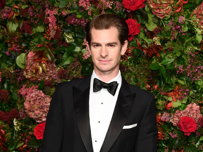 Andrew Garfield in tuxedo against a flower wall