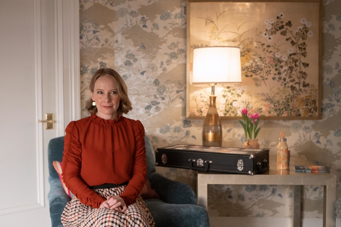 Amy Ryan in a red blouse and plaid skirt