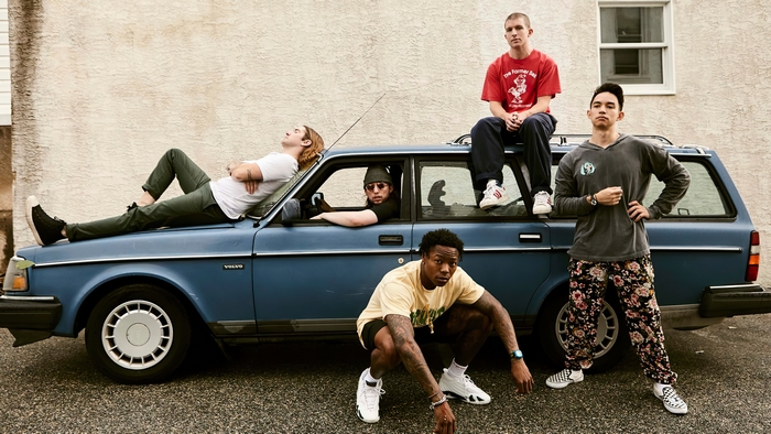Turnstile band members posing with a blue Volvo wagon