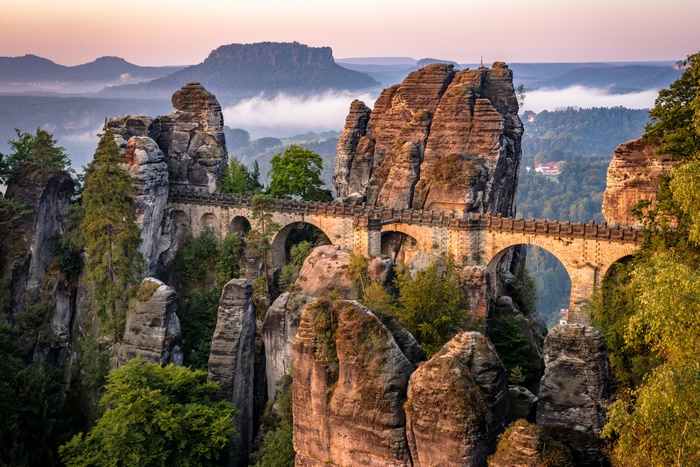 Ancient stone bridge among towering rock formations at sunrise