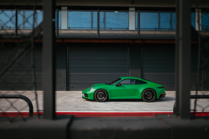 Green Porsche 911 Carrera GTS sport car behind a fence