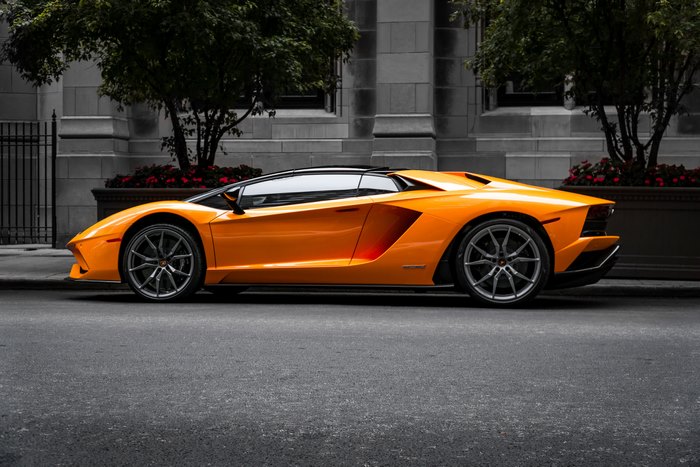 Orange Lamborghini Aventador S parked on city street