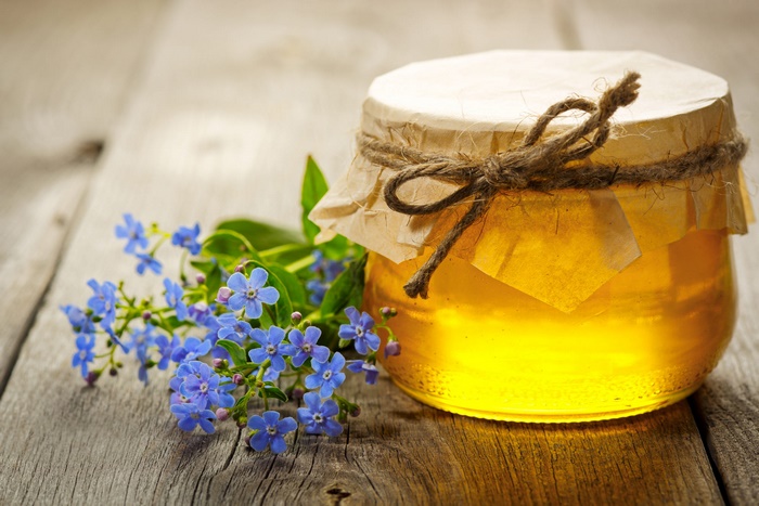 Golden honey jar and blue forget-me-not flowers