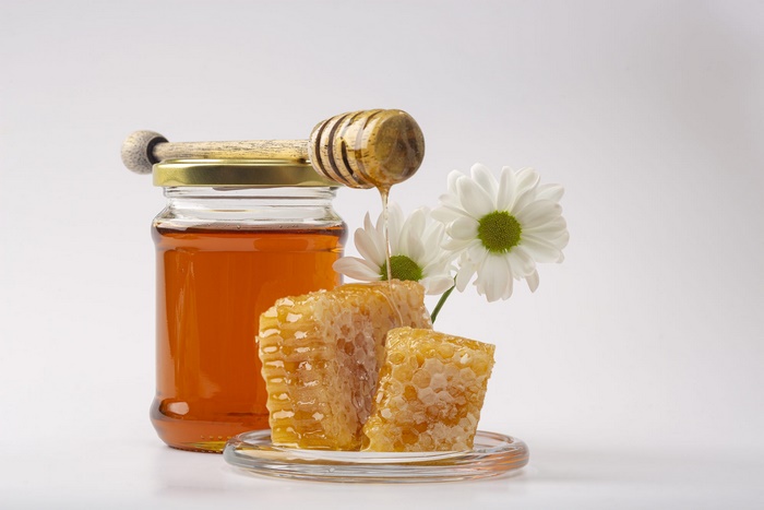 Golden honey, honeycomb, and white daisies