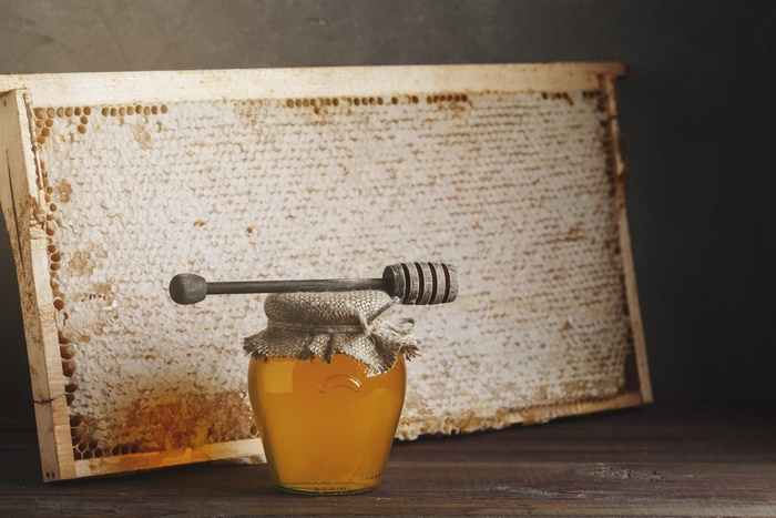 Golden honey jar with dipper and honeycomb