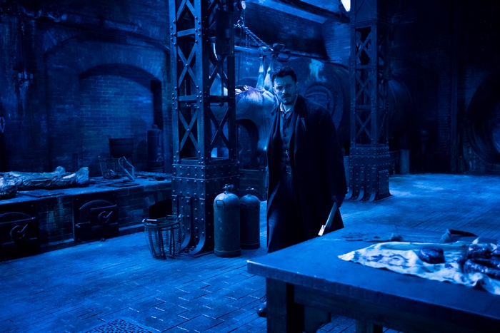 Rycroft Philostrate in a dark blue, grim industrial room