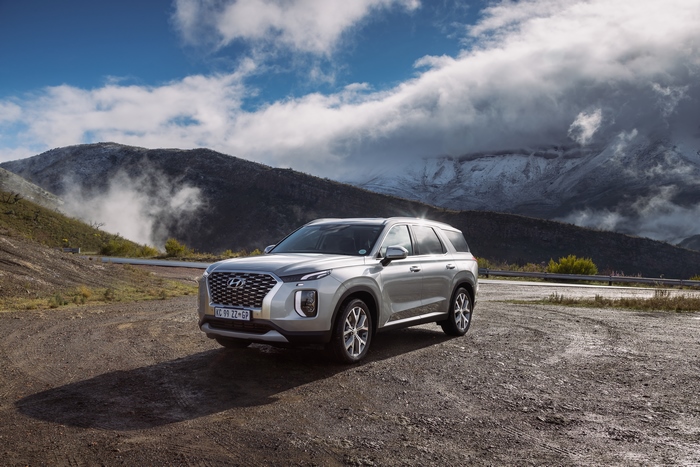 Hyundai Palisade SUV with snowy mountains and clouds