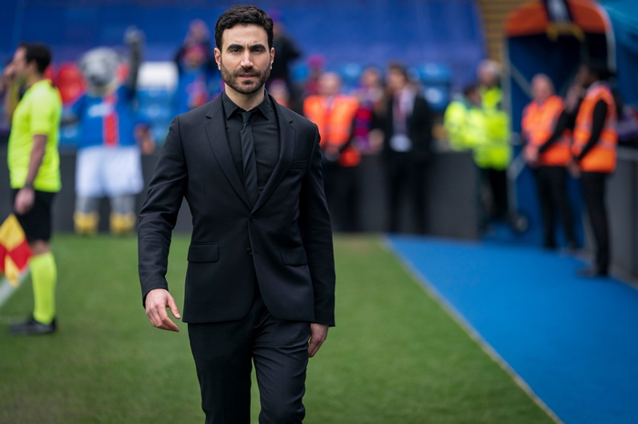 Brett Goldstein in black suit on football pitch