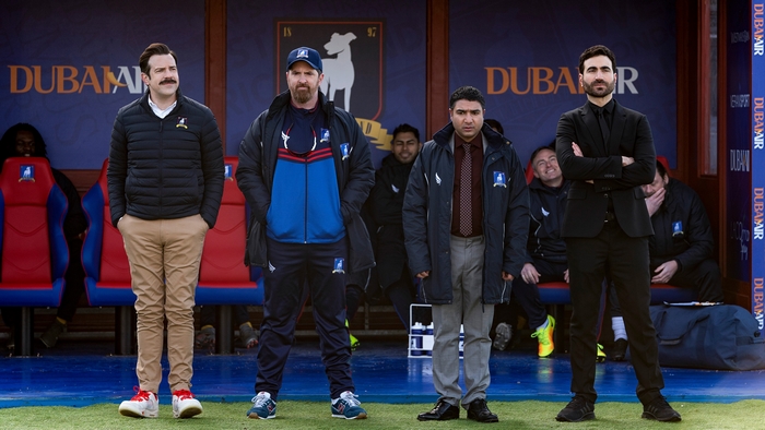 Ted Lasso and coaches on soccer field sideline