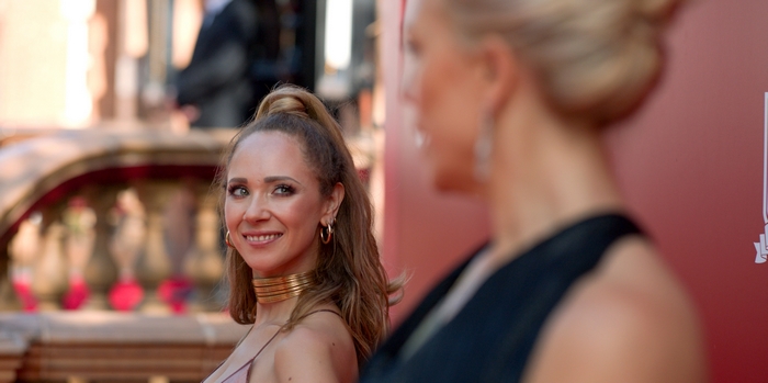 Juno Temple from Ted Lasso smiling, wearing gold choker