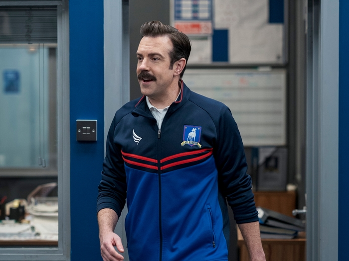 Jason Sudeikis as Ted Lasso in blue tracksuit smiling