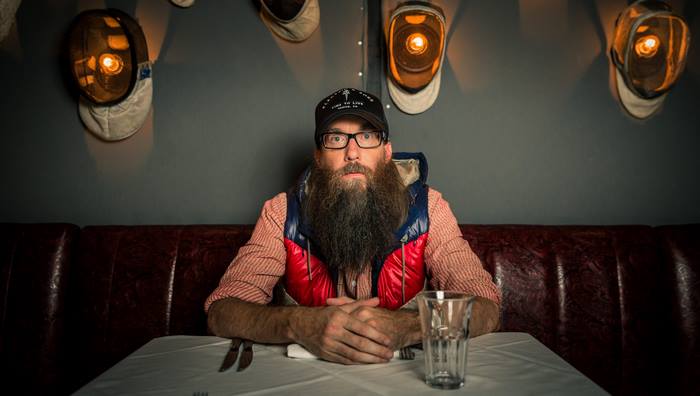 Crowder with a long beard in a restaurant booth