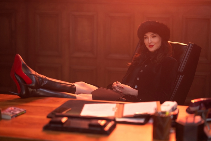 Gal Gadot in fur hat with boots on office desk