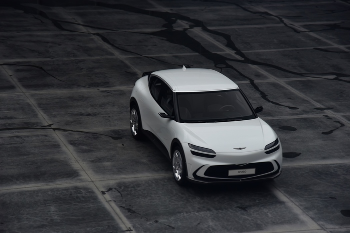White Genesis GV60 SUV on dark textured ground