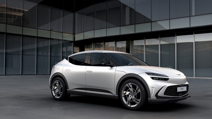 Silver Genesis GV60 SUV in front of modern building