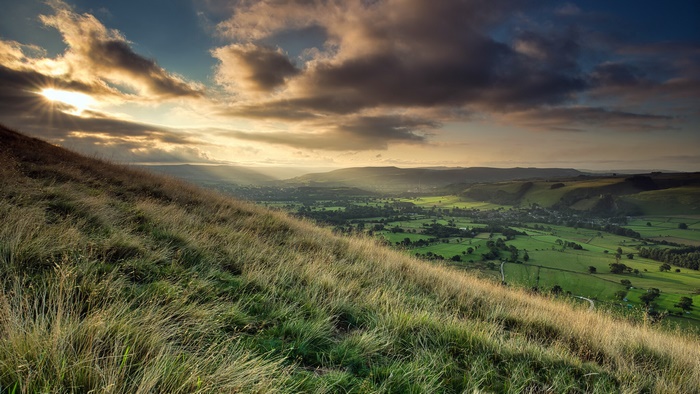 Dramatic sunset over a green valley and hillside