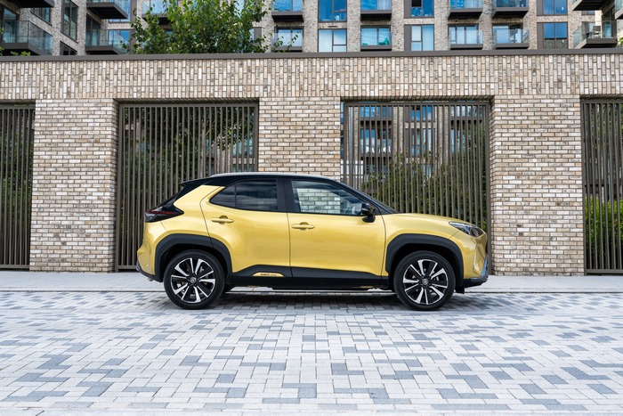 Yellow Toyota Yaris Cross Hybrid SUV by brick building