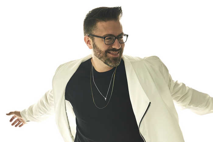 Danny Gokey smiling in white jacket and glasses