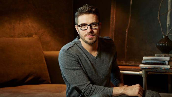 Danny Gokey in glasses sitting on a couch