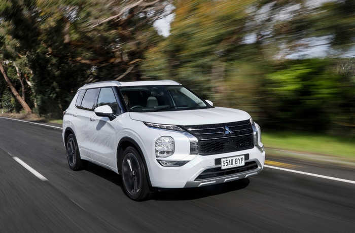 White Mitsubishi Outlander SUV driving on a road