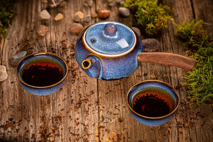 Blue Glazed Teapot and Tea Cups on Rustic Wood