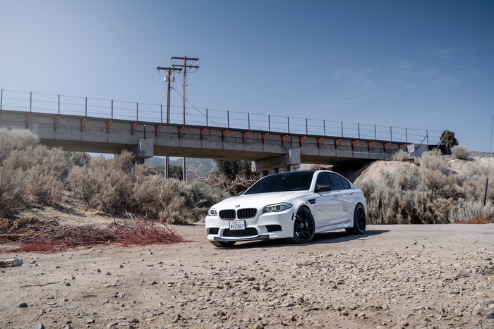 White BMW 5 Series luxury car under bridge