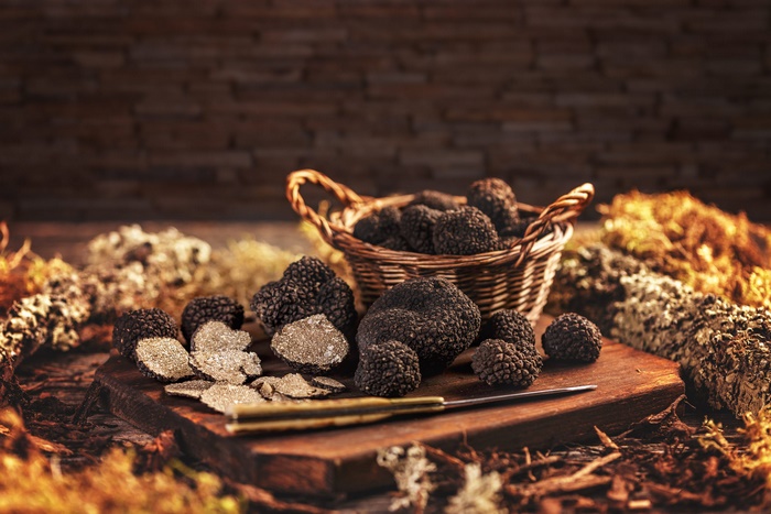 Black Truffles, Sliced and Whole, on Wooden Board