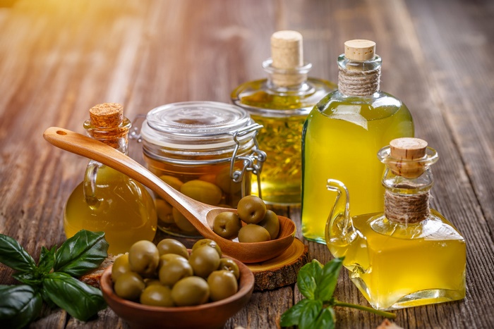 Fresh olive oil, green olives, and basil on wood