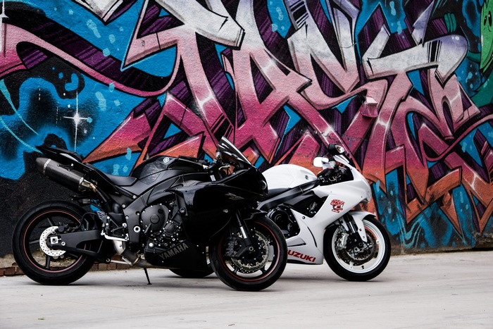 Yamaha and Suzuki motorcycles against colorful graffiti wall