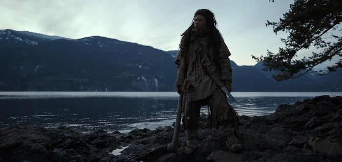 Franz Drameh as a rugged warrior by a mountain lake