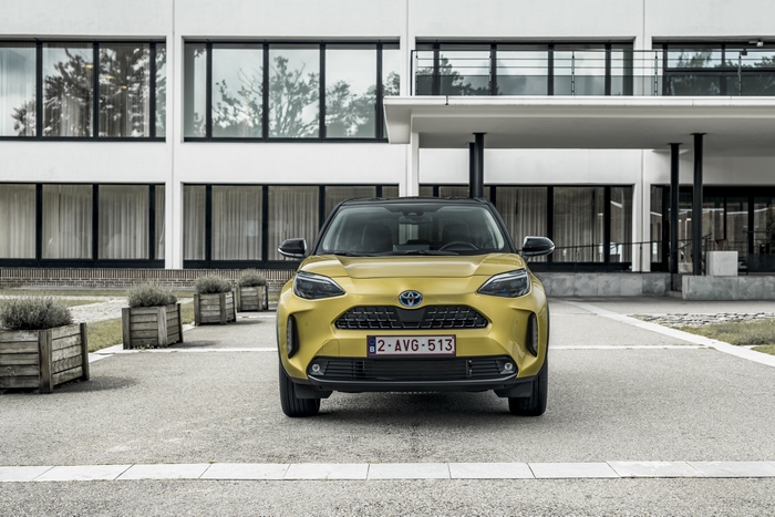 Yellow Toyota Yaris Cross Hybrid SUV in front of building