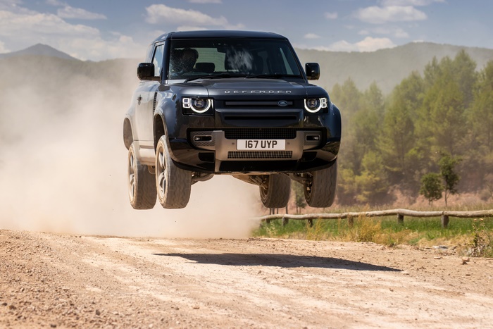 Land Rover Defender 90 SUV jumping on a dirt road