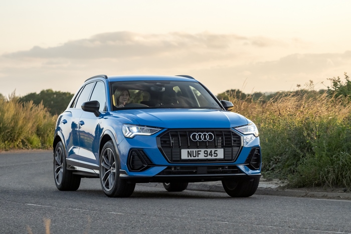 Blue Audi Q3 luxury SUV driving at sunset