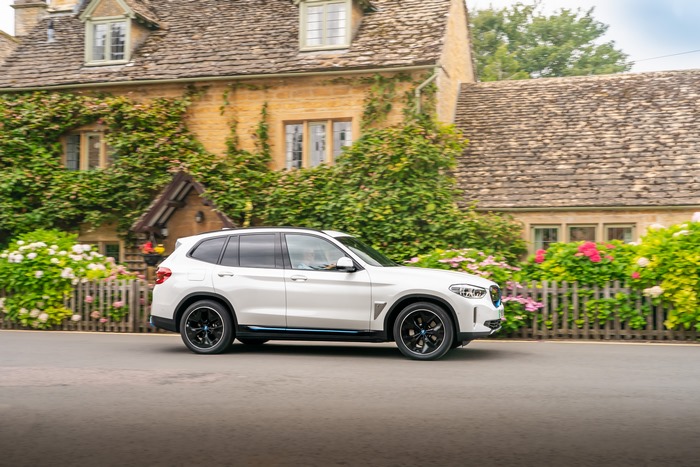 White BMW iX3 Electric SUV driving in a village