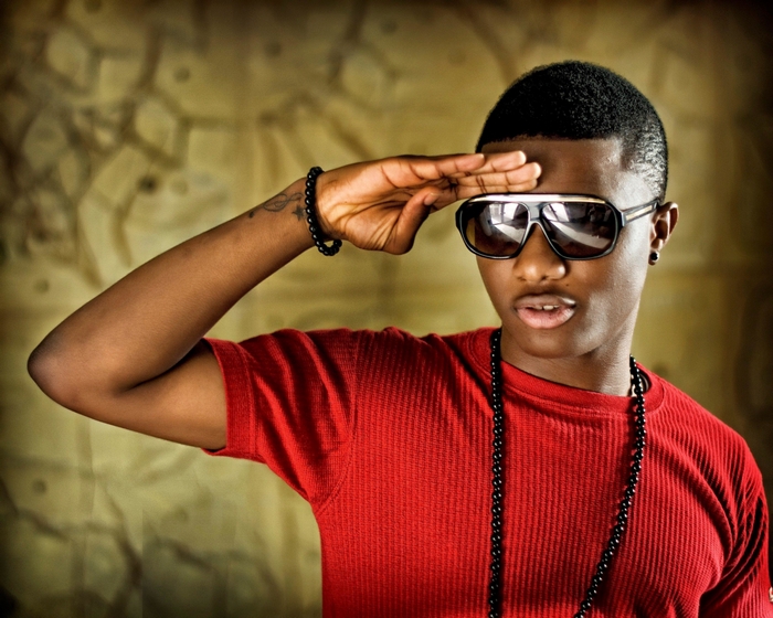 WizKid in red shirt with sunglasses, hand to forehead