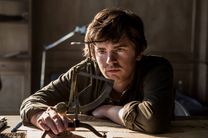 Freddie Highmore intently examining an instrument in The Vault