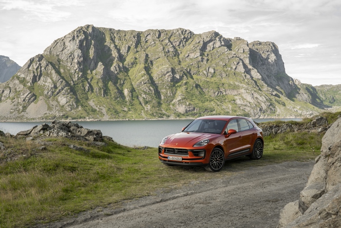 Orange Porsche Macan S SUV in a mountainous landscape