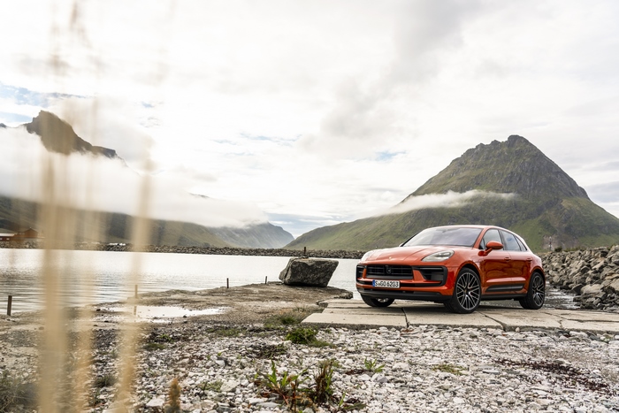 Orange Porsche Macan S SUV in a scenic mountain landscape