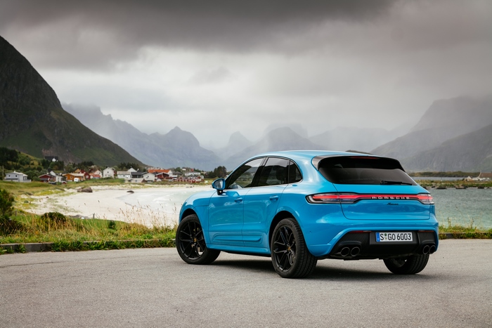 Blue Porsche Macan SUV in a stunning coastal mountain landscape