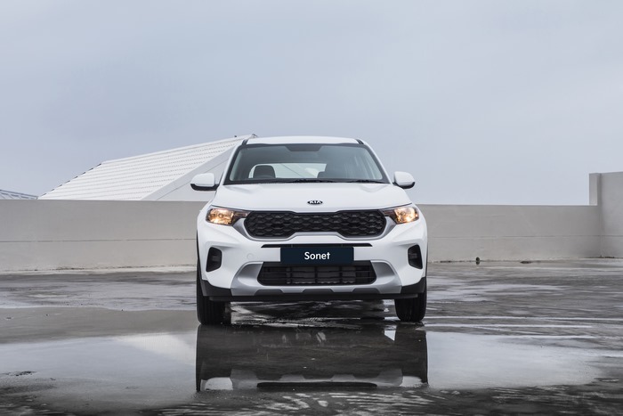 White Kia Sonet SUV on wet ground with reflection
