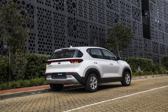 White Kia Sonet LX SUV parked by modern building 4K