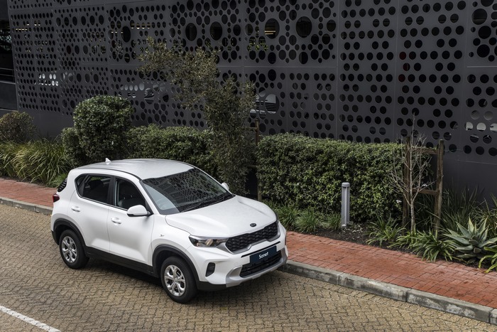 White Kia Sonet SUV in front of modern building